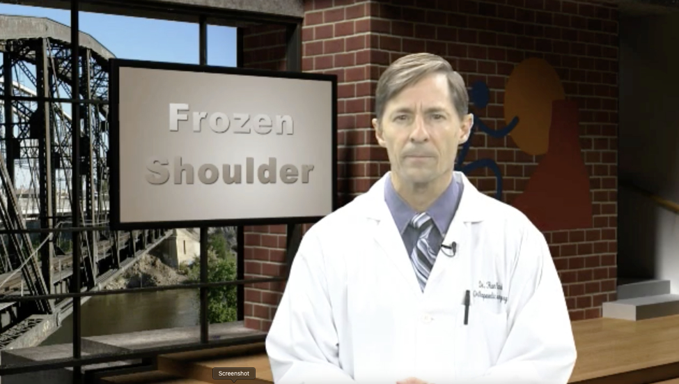 A doctor standing in front of a screen that says Frozen Shoulder
