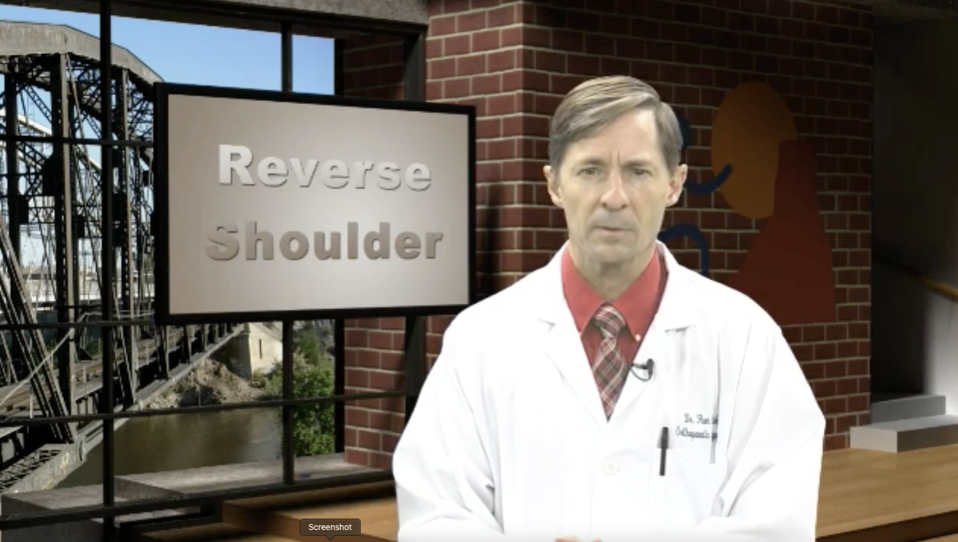 Doctor standing in front of a screen that says “Reverse Shoulder”